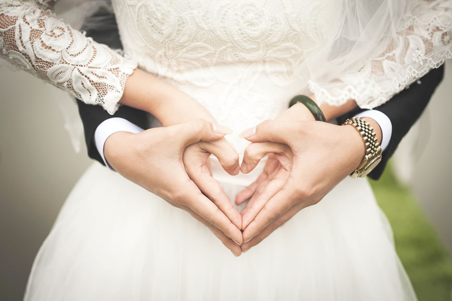 bride and groom making heart shape with hands