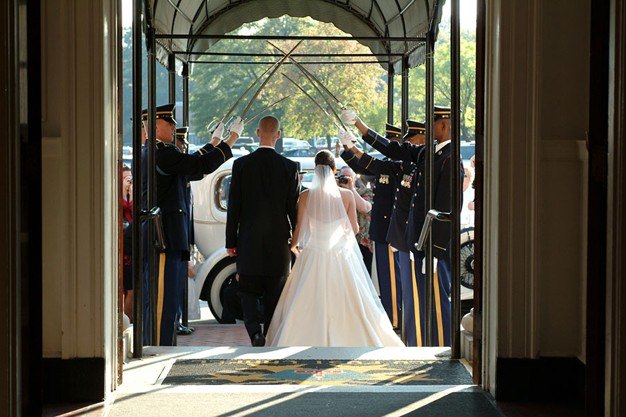 bride and groom walking under military swords